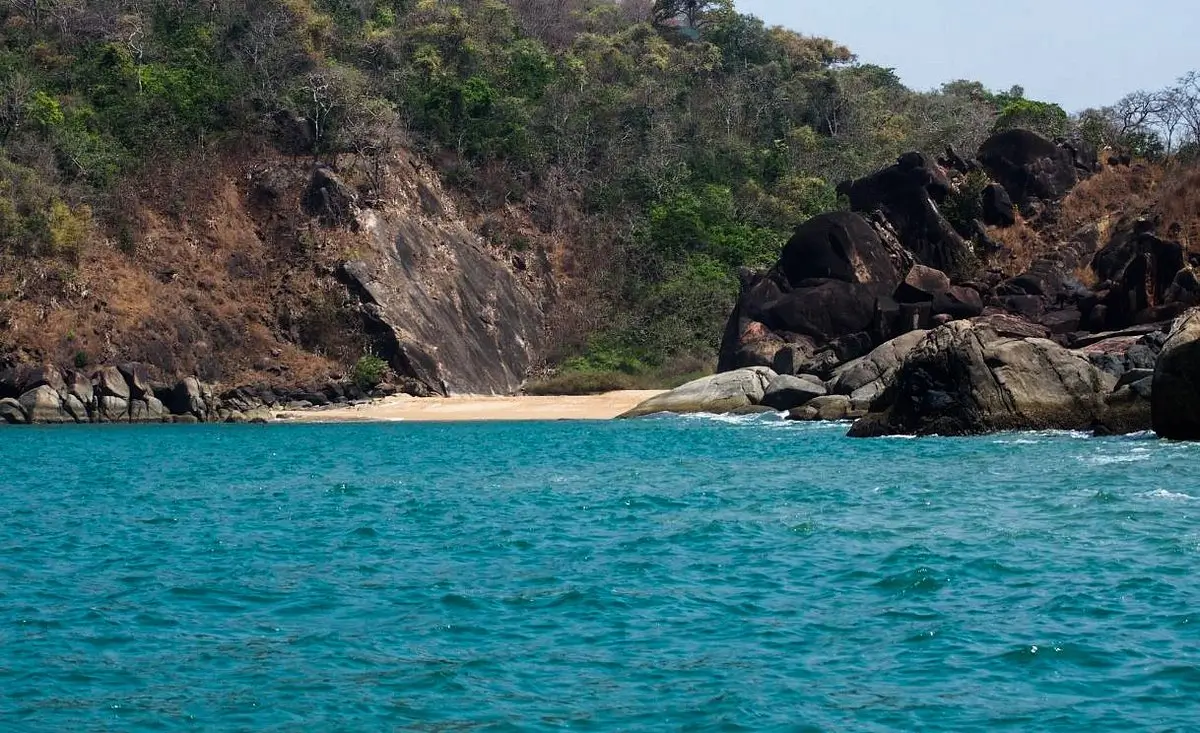 Butterfly Beach: A scenic beach featuring rocks and water, set against a majestic cliff backdrop.