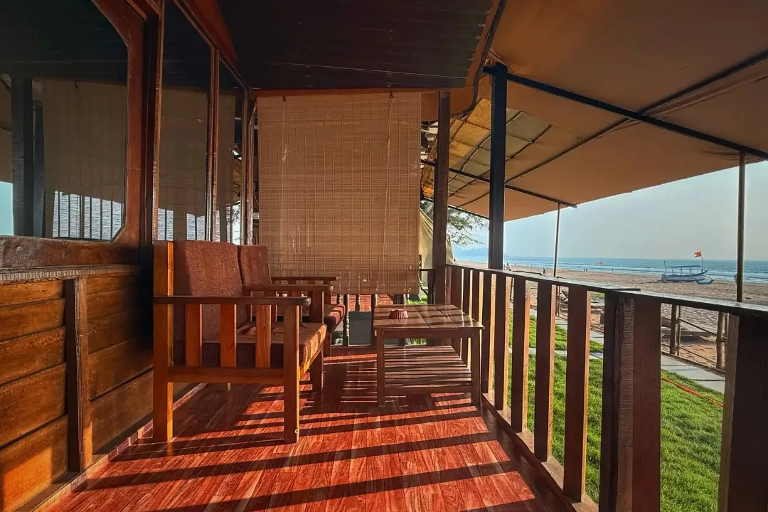  A serene beach view framed by the wooden structure of a cozy house, showcasing sand and waves in the distance.