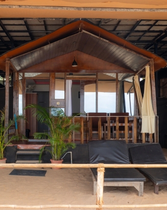 A beach hut featuring a wooden deck and a rustic wooden table, set against a serene coastal backdrop.