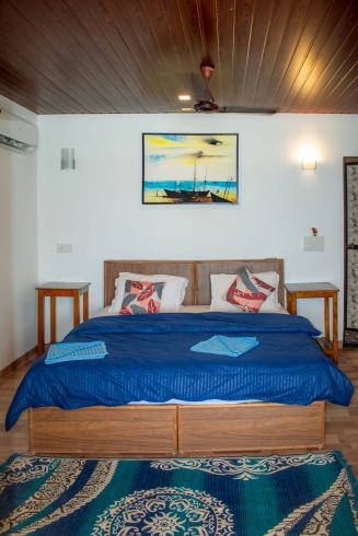 A neatly made bed in the Elevated Seafacing Huts Room, featuring soft linens and a warm ambiance.