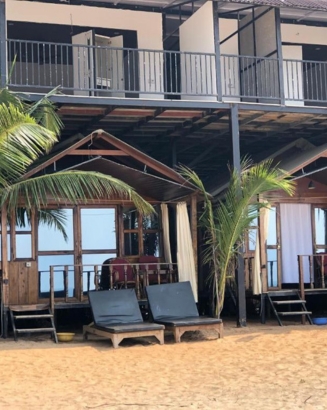 A picturesque beach hut with a wooden deck and table, perfect for enjoying the coastal view.