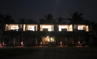 A nighttime view of the beach huts illuminated by warm lights, creating a cozy and inviting atmosphere.