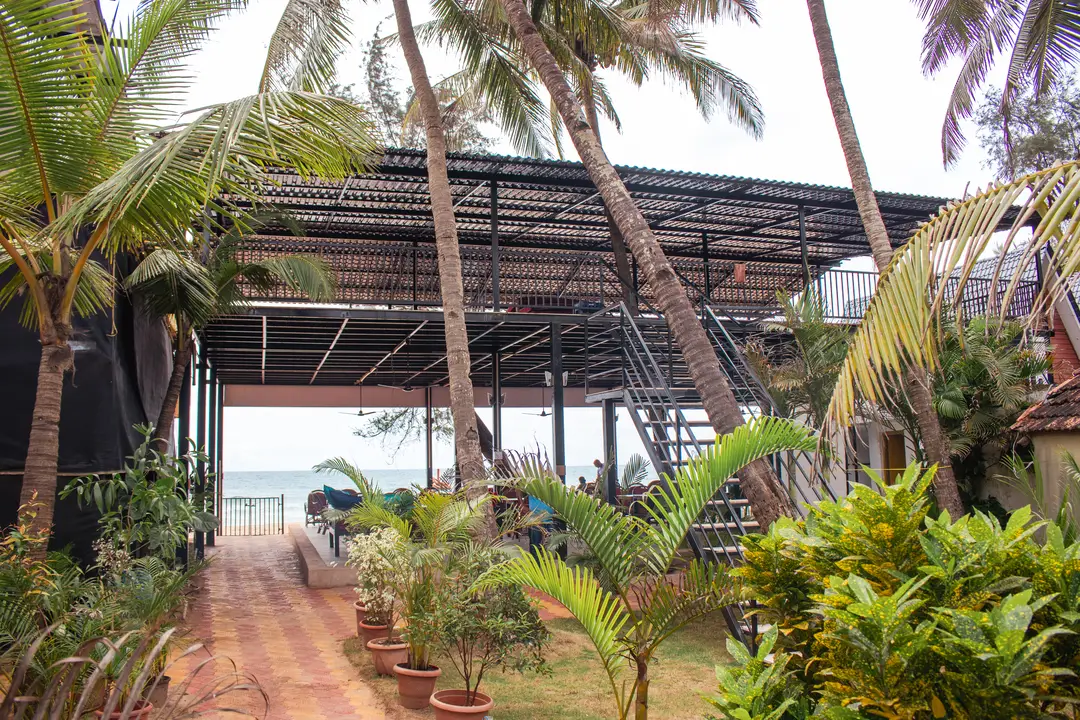 A scenic view of a restaurant with a patio, adjacent to a sandy beach, highlighting a peaceful seaside retreat.