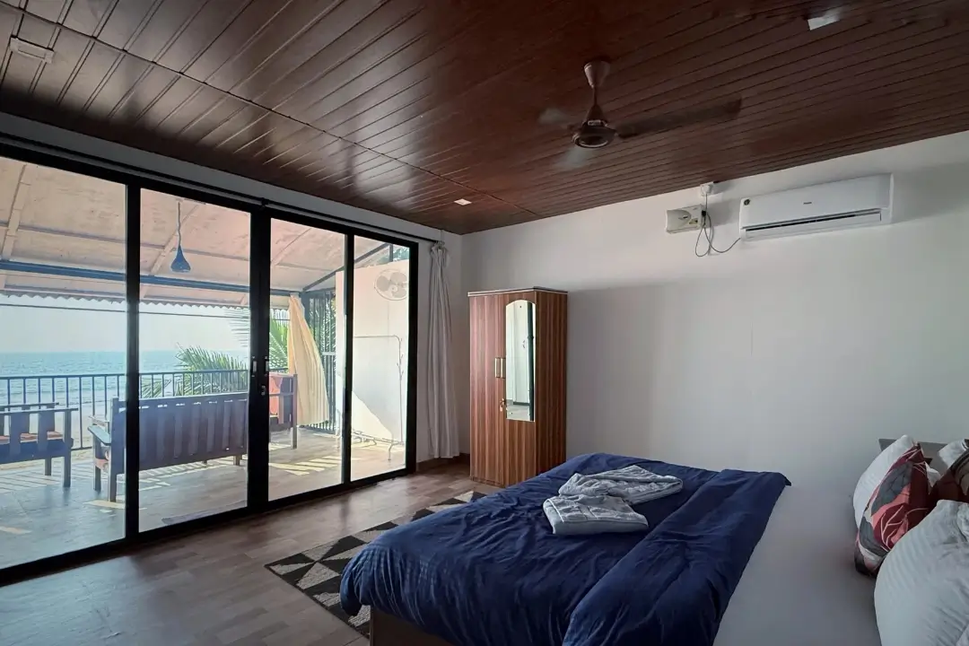 A serene bedroom featuring a balcony that offers a stunning view of the ocean waves and horizon.