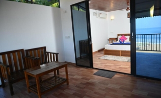 A serene bedroom featuring a balcony that offers a stunning view of the ocean waves and horizon.