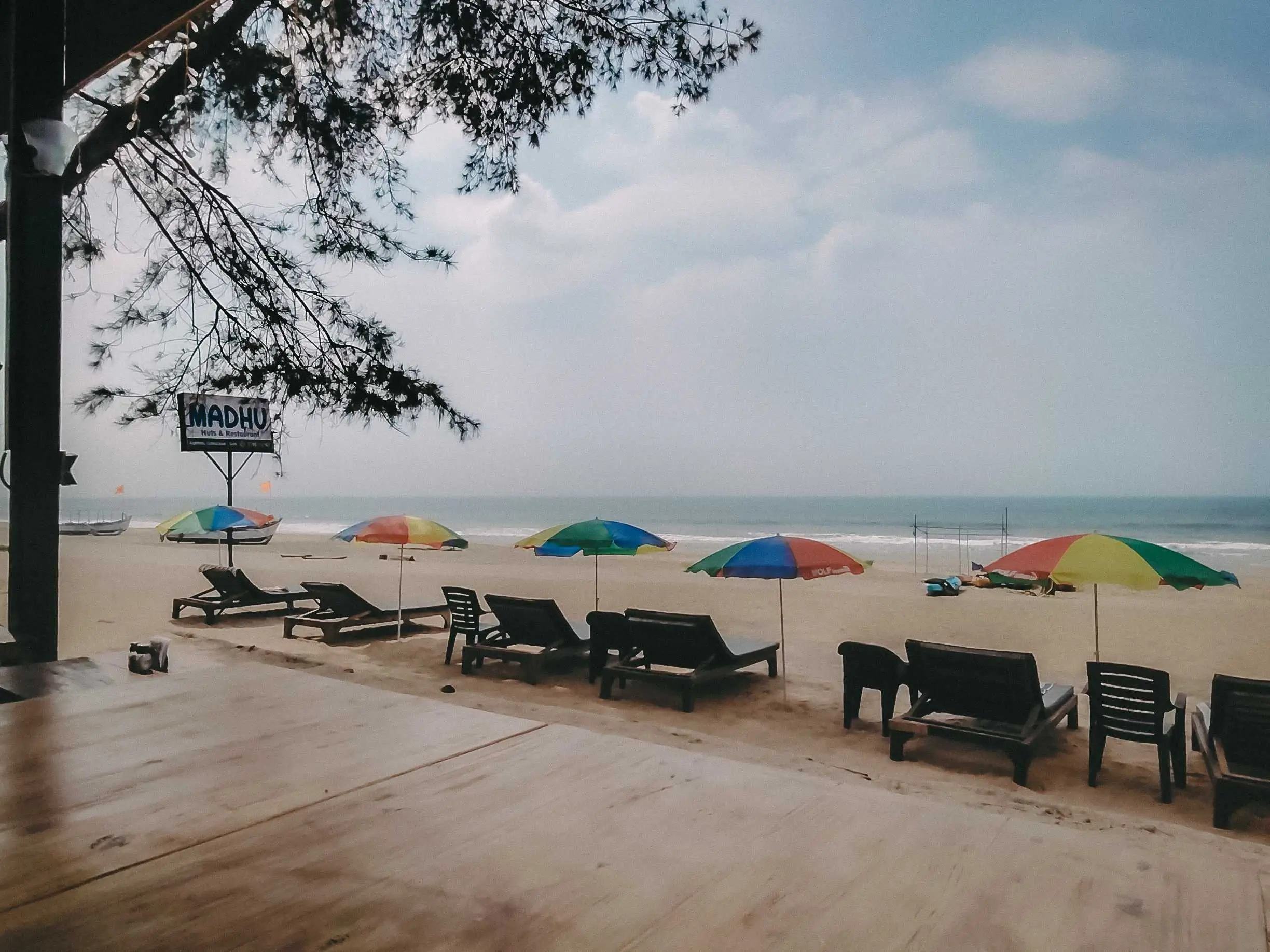 A picturesque beach hut with a wooden deck and table, perfect for enjoying the coastal view.